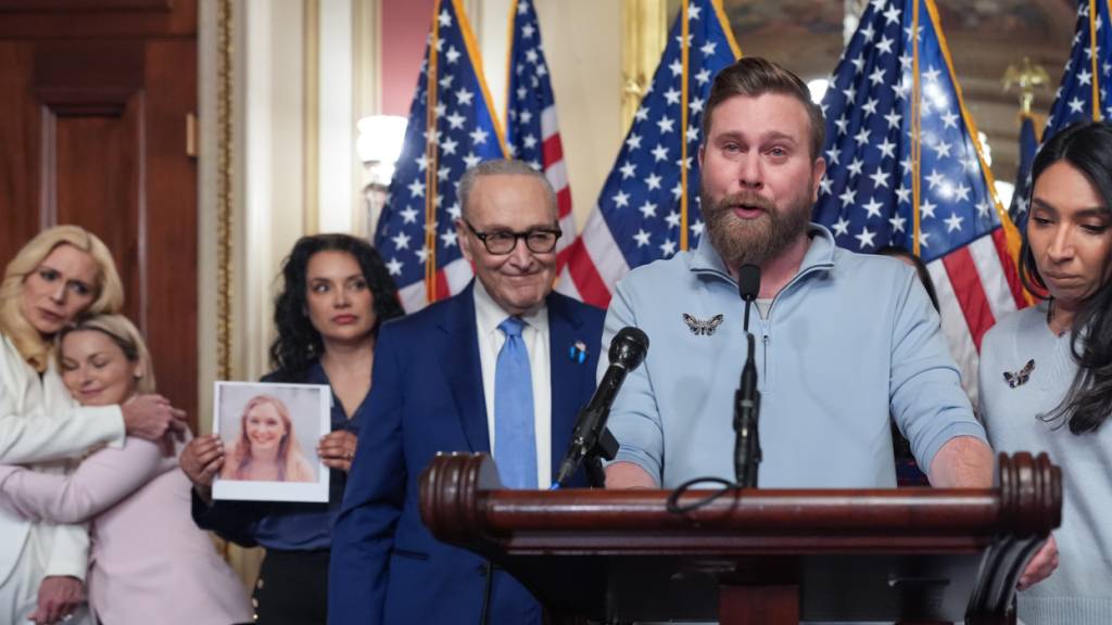 ARCHIV - Sky Roberts, der Bruder von Virginia Giuffre, spricht zusammen mit seiner Frau Amanda (r) während Senatsminderheitenführer Chuck Schumer, D-N.Y., zuhört und Überlebende des verurteilten Sexualstraftäters Jeffrey Epstein und Gesetzgeber sich versammeln. Foto: J. Scott Applewhite/AP/dpa