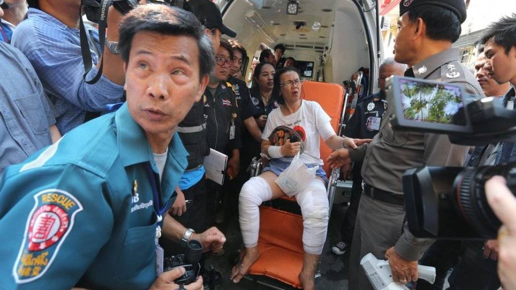 Eine verletzte Frau (m) wird von Rettungskräften umsorgt. Bei der Explosion eines Taxiboots in Bangkok wurden mehrere Menschen verletzt