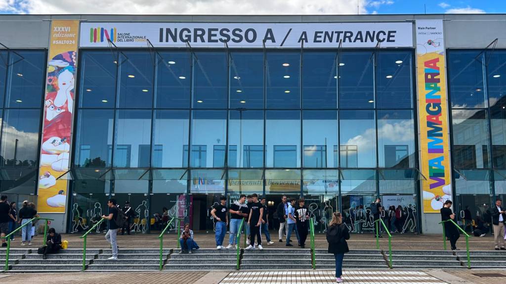 Menschen stehen an einem Eingang zur Buchmesse Salone Internazionale del Libro in Turin. Schwerpunkt der Messe ist in diesem Jahr deutschsprachige Literatur. Foto: Christoph Sator/dpa - ACHTUNG: Verwendung nur im vollen Format