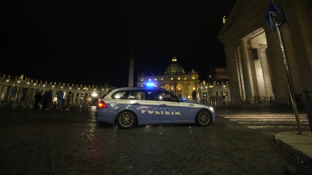 Ein italienisches Polizeiauto fährt am späten Abend vor dem Petersplatz im Vatikan vorbei. Foto: Andrew Medichini/AP/dpa