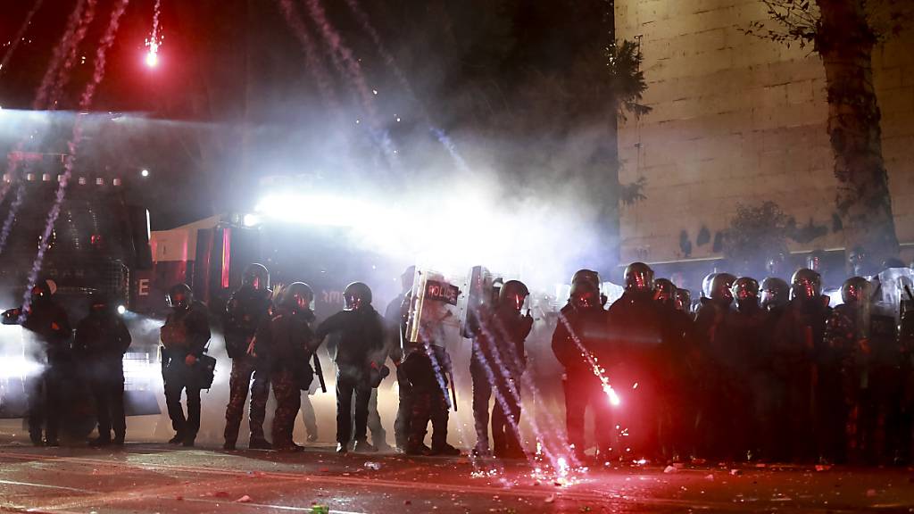 Demonstranten werfen Pyrotechnik und Feuerwerk auf Polizisten. Foto: Zurab Tsertsvadze/AP/dpa