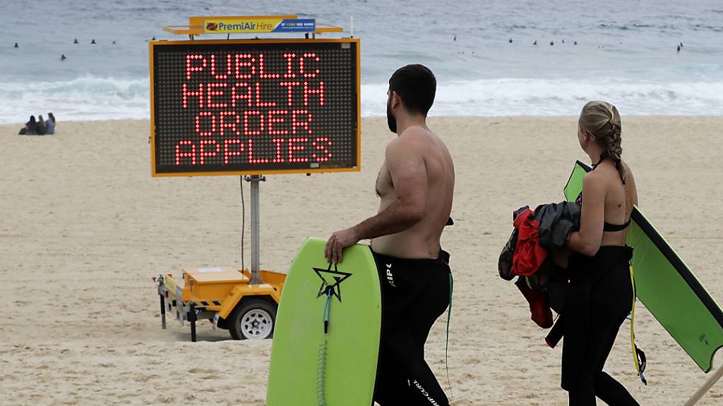 Ein Schild weist Menschen an einem Strand in Sydney auf Einschränkungen hin.