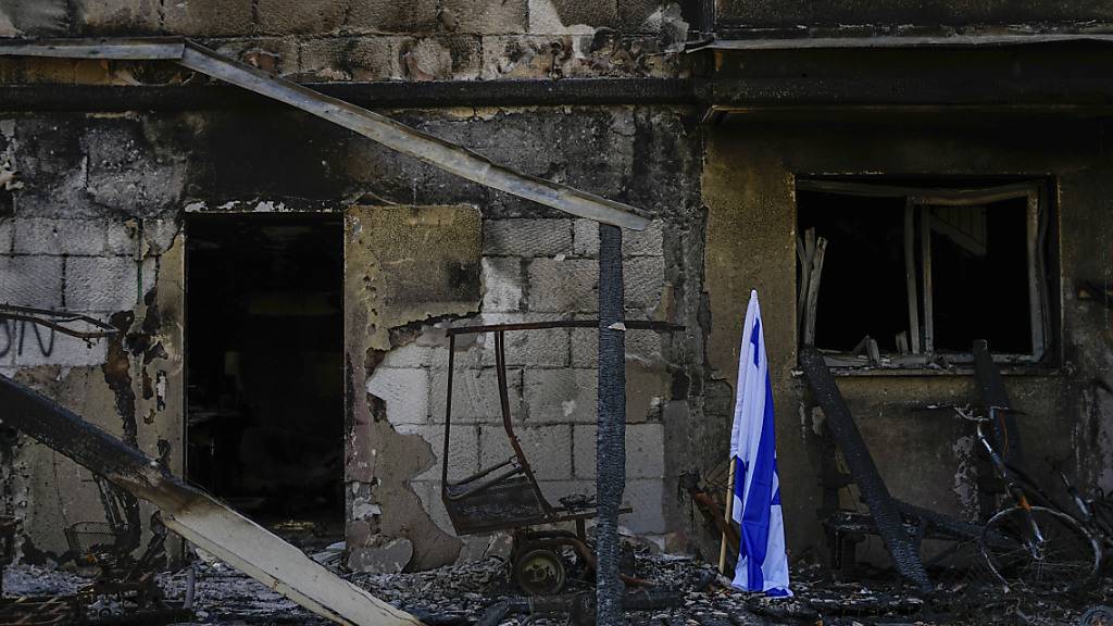 ARCHIV - Eine israelische Fahne steht neben einem von der Hamas zerstörten Haus. Foto: Ariel Schalit/AP/dpa