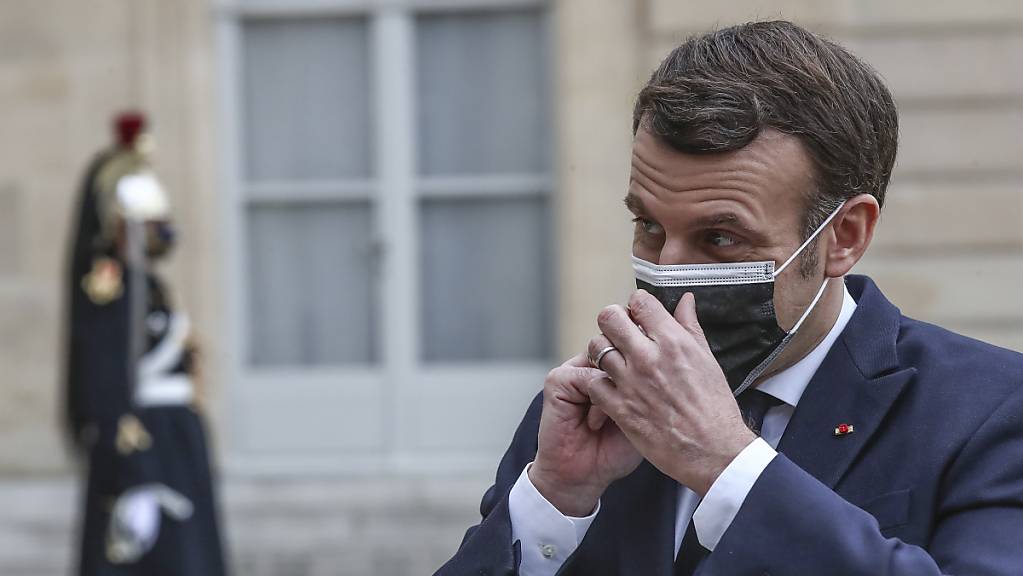 Emmanuel Macron, Präsident von Frankreich, setzt seinen Mund-Nasen-Schutz. Foto: Michel Euler/AP/dpa