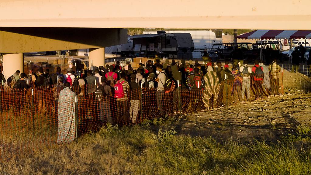 Migranten, viele von ihnen aus Haiti, warten in Schlangen auf Busse unter der Del Rio International Bridge in Del Rio, Texas.