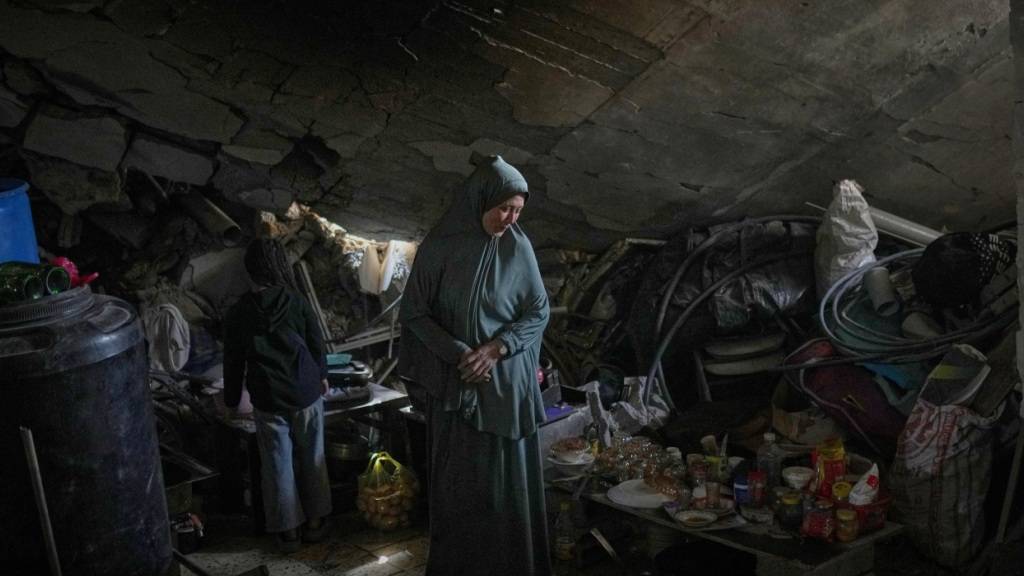 Khadija Abu Shaqfa und ihre Tochter Rita gehen durch die Küche ihres beschädigten Hauses, in dem Lebensmittel und Töpferwaren inmitten der Trümmer liegen. Foto: Jehad Alshrafi/AP/dpa