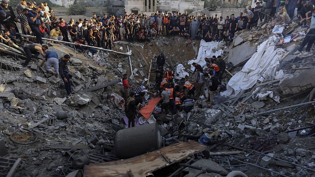 dpatopbilder - Palästinenser versammeln sich vor den Überresten eines zerstörten Hauses in Gaza-Stadt. Foto: Abed Khaled/AP/dpa