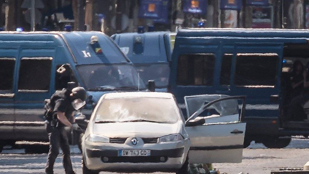 Sprengstoffexperten untersuchen das Angreifer-Auto auf den Pariser Champs-Elysées.