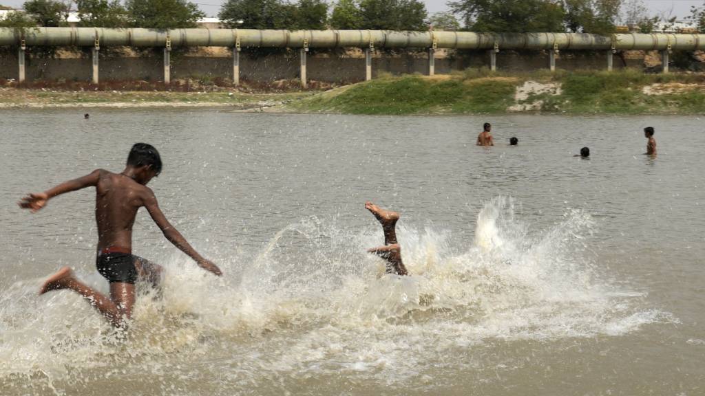 Kinder kühlen sich in einem See in Neu Delhi ab. Dortige Temperaturen sind auf 52,3 Grad gestiegen - so heißt war es seit Messbeginn vor über einem Jahrhundert noch nie. Foto: Manish Swarup/AP