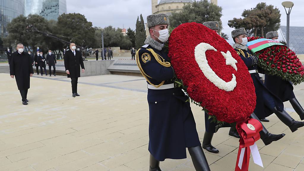 Recep Tayyip Erdogan (hinten, l), Staatspräsident der Türkei, und Ilham Alijew (hinten, r), Präsident von Aserbaidschan, nehmen an einer Kranzniederlegung teil. Zuvor waren sie bei einer Militärparade, mit der Aserbaidschan seinen «Sieg» im Krieg um die Südkaukasus-Region Berg-Karabach feierte. Foto: -/Turkish Presidency/AP/dpa