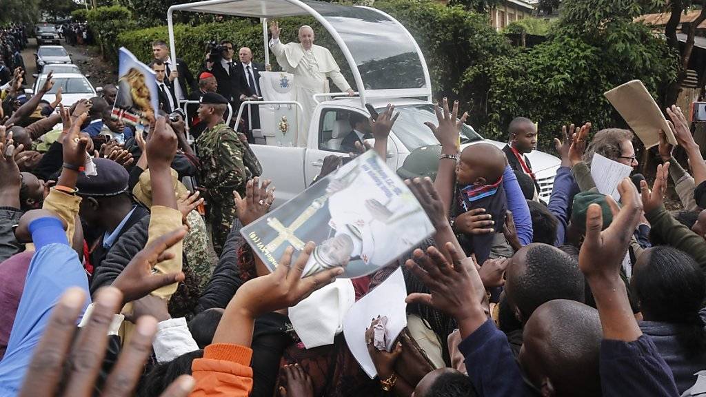 Im offenen Papamobil fährt der Papst durch Kangemi. In seiner Rede verurteilt er anschliessend, dass viele Menschen durch Ungerechtigkeit und Profitgier in die Armut getrieben werden.