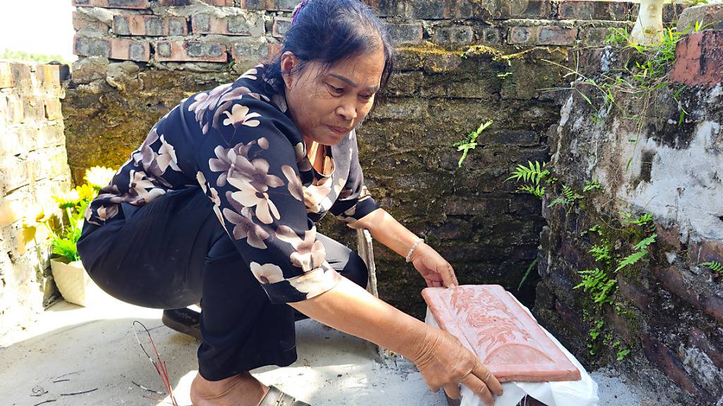 PRODUKTION - Nguyen Thi Nhiem wählt rechteckige Tongefäße aus, in denen sie die Föten in Massengräbern beerdigt. Foto: Bac Pham/dpa