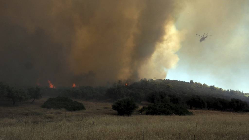 ARCHIV - Ein Hubschrauber fliegt über einem Waldbrand in der Nähe des Dorfes Vatontas. Foto: Thodoris Nikolaou/AP/dpa