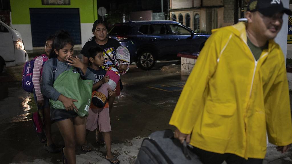 Eine Familie geht in eine Notunterkunft, um sich vor den Auswirkungen des herannahenden Hurrikans «Berly» zu schützen. Foto: Felix Marquez/dpa
