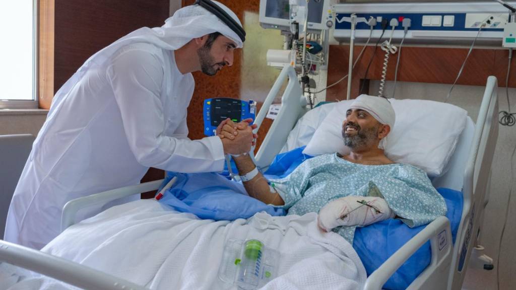 HANDOUT - Auf diesem Foto, das vom Medienbüro der Regierung von Dubai zur Verfügung gestellt wurde, besucht der Kronprinz von Dubai, Scheich Hamdan bin Mohammed bin Rashid Al Maktoum (l) den verletzten indischen Flydubai-Kapitän Smit Machchhar in einem Krankenhaus in Abu Dhabi, Vereinigte Arabische Emirate. Foto: Uncredited/Government of Dubai Media Office/AP/dpa