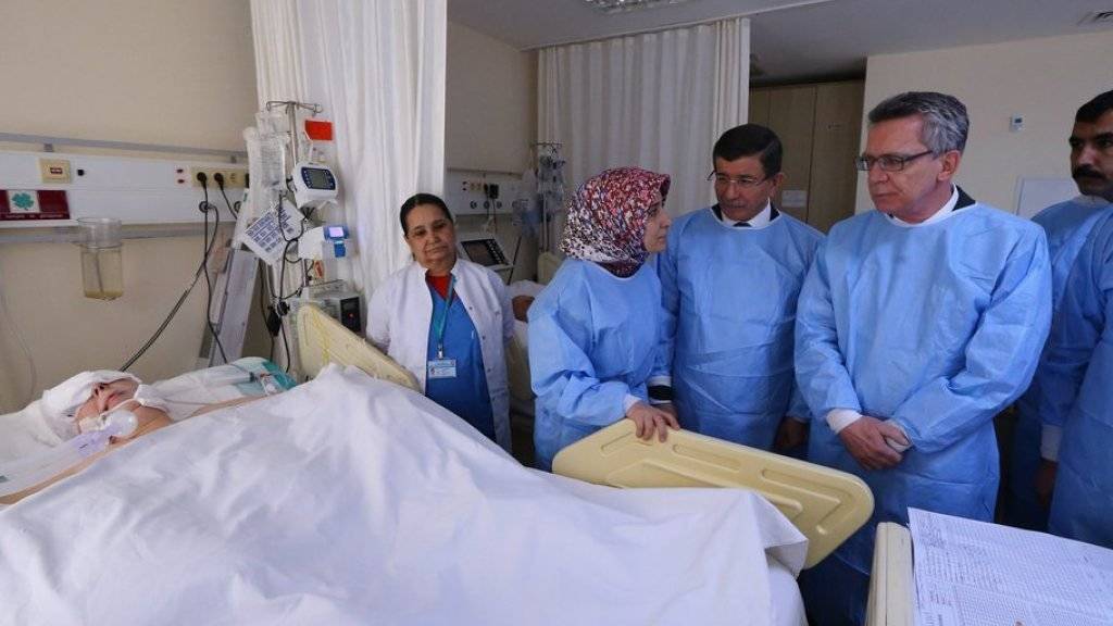 Der deutsche Innenminister Thomas de Maizière (2. von rechts) und der türkische Ministerpräsident Ahmet Davutoglu (Mitte) besuchen am Mittwoch in einem Spital in Istanbul einen Schwerverletzten.