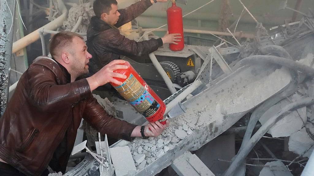 dpatopbilder - Männer löschen ein Feuer in einer Parfüm- und Kosmetikfabrik, die durch einen russischen Angriff in Charkiw zerstört wurde. Foto: Andrii Marienko/AP/dpa