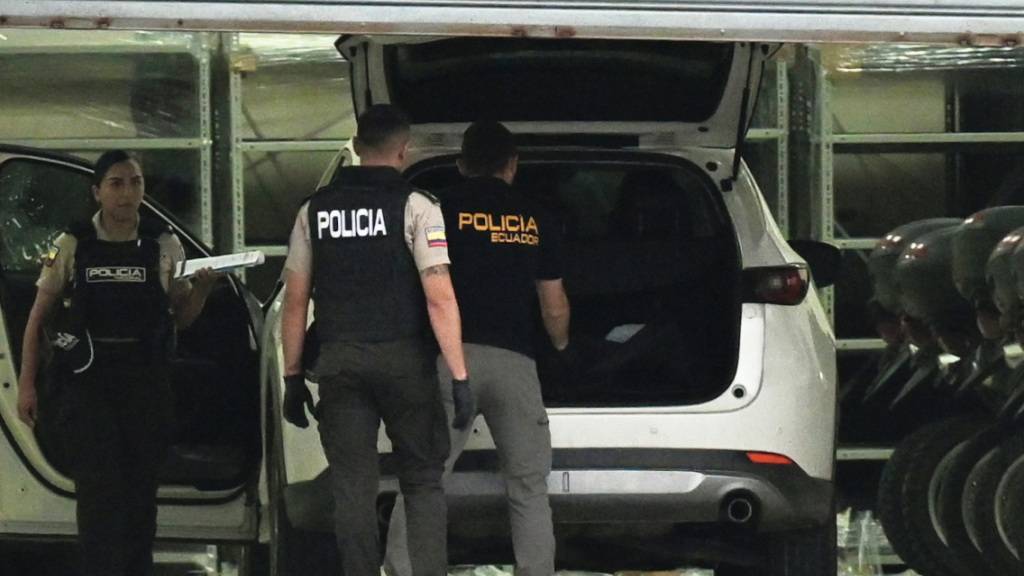 Polizisten in Schutzwesten untersuchen das Auto des erschossenen Staatsanwalts César Suárez in Guayaquil, Ecuador. Während sich kriminelle Banden und staatliche Sicherheitskräfte in Ecuador heftige Kämpfe liefern, ist ein für die Ermittlungen gegen die organisierte Kriminalität zuständiger Staatsanwalt getötet worden. Foto: -/dpa