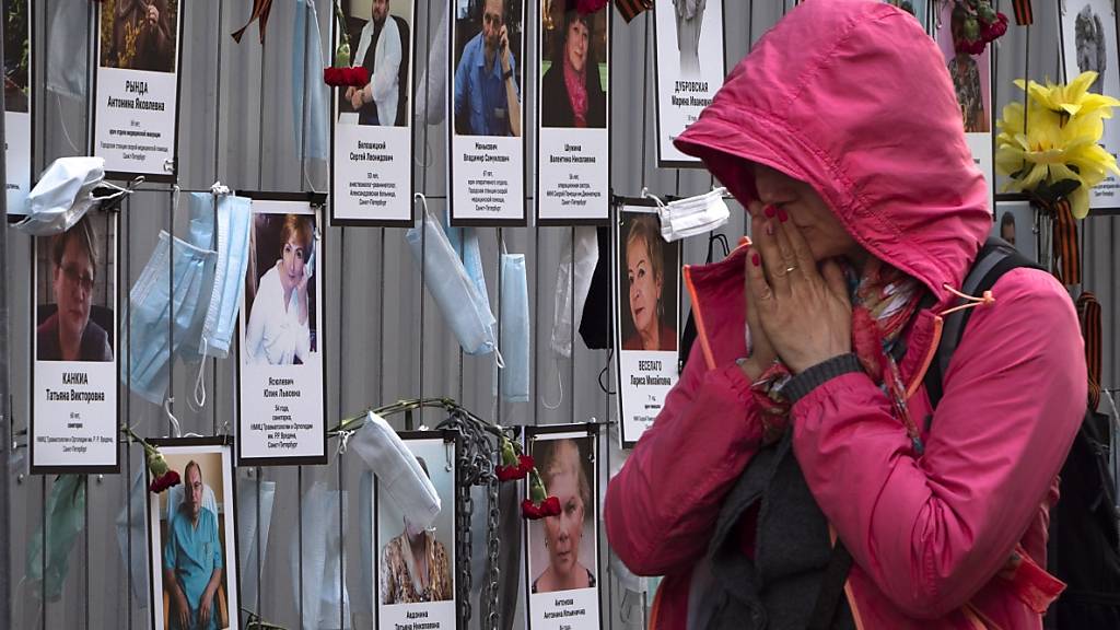 Eine Frau reagiert als sie an einer inoffiziellen Gedenkstätte für St. Petersburger Medizinern vorbeigeht, die während ihrer Arbeit am Coronavirus erkrankt sind und daran gestorben sind. Foto: Dmitri Lovetsky/AP/dpa