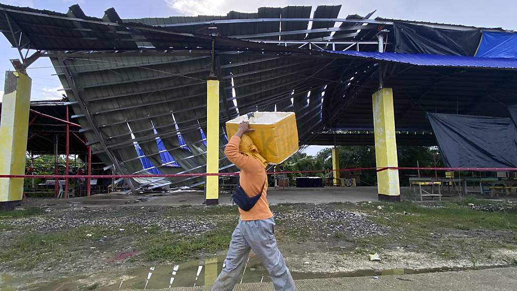 Ein Fischverkäufer geht an einem eingestürzten Gebäude vorbei: Vor der Küste der Insel Mindanao hat sich ein starkes Erdbeben ereignet. Tsunami-Wellen drohten im Anschluss. Foto: Ivy Marie Mangadlao/AP