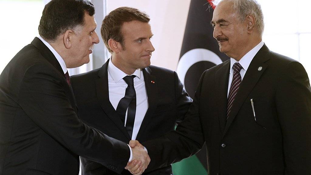 Der französische Präsident Emmanuel Macron (Mitte) begrüsst den Chef der libyschen Übergangsregierung Fajis al-Sarradsch (links) und den im Osten Libyens mächtigen General Chalifa Haftar (rechts) zu den Verhandlungen bei Paris.