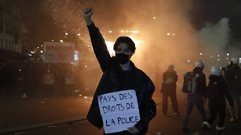 Ein Teilnehmer einer Demonstration hält während eines Protestes gegen ein neues Sicherheitsgesetz ein Schild mit der Aufschrift «Land der Polizeirechte» in der Hand. Foto: Francois Mori/AP/dpa