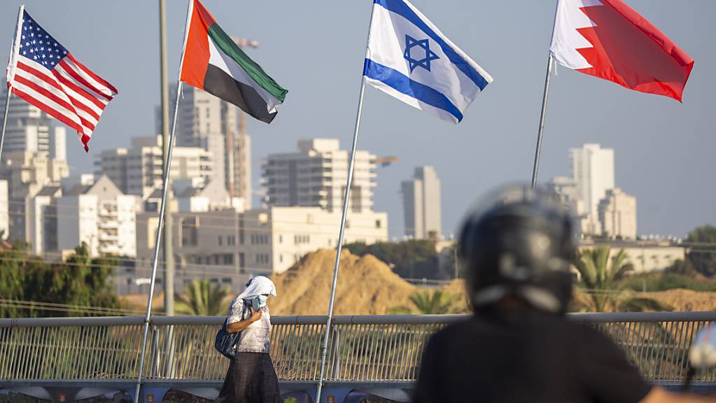 Eine Frau geht an den Flaggen der USA, der Vereinigten Arabischen Emirate, Israels und Bahrains vorbei.