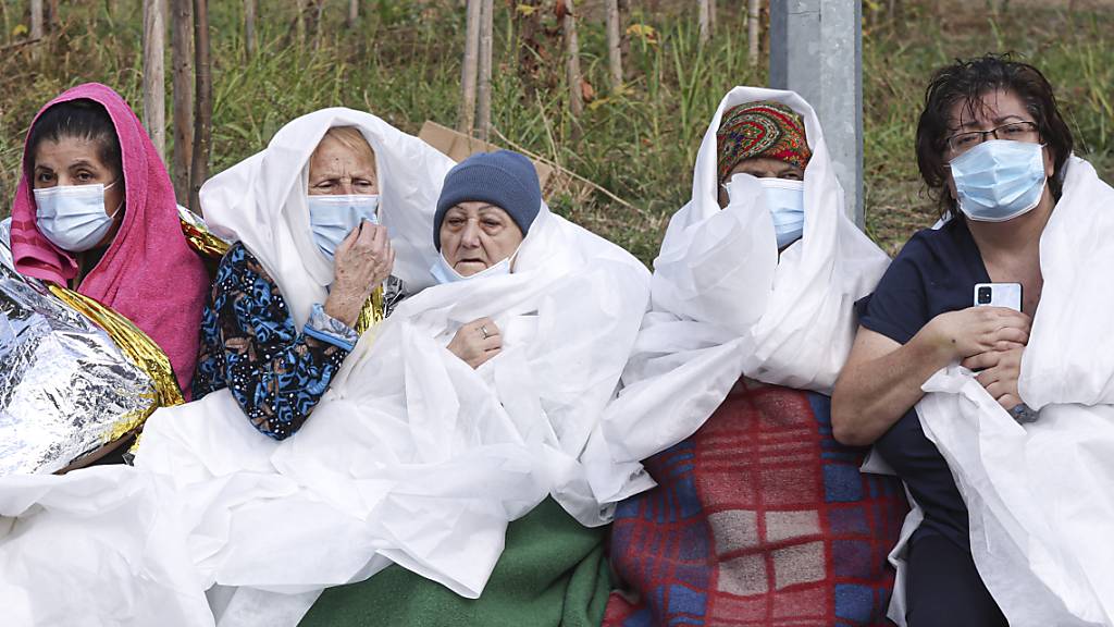 Frauen tragen Mund-Nasen-Schutz und sind in Decken und Laken gewickelt. In der rumänischen Schwarzmeer-Stadt Constanta sind bei einem Großbrand in einem Krankenhaus für Infektionskrankheiten nach Angaben des Katastrophenschutzes sieben Menschen ums Leben gekommen. Foto: Costin Dinca/AP/dpa
