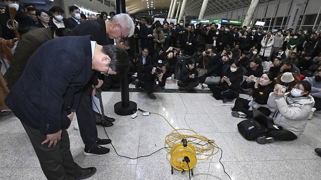 dpatopbilder - Der CEO von Jeju Air, Kim E-bae (l), und andere Mitglieder der Geschäftsführung verbeugen sich auf dem internationalen Flughafen Muan vor den Angehörigen der Passagiere. Foto: Uncredited/YONHAP/AP/dpa