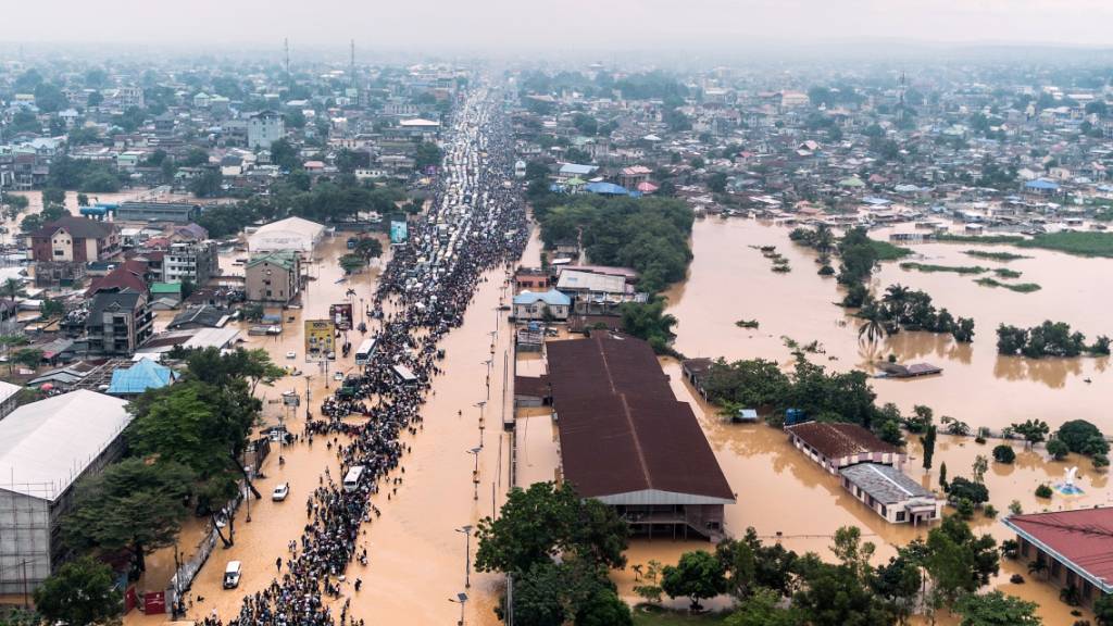 dpatopbilder - Menschen laufen nach heftigen Regenfällen durch die überfluteten Straßen der Hauptstadt der Demokratischen Republik Kongo. Foto: Samy Ntumba Shambuyi/AP/dpa