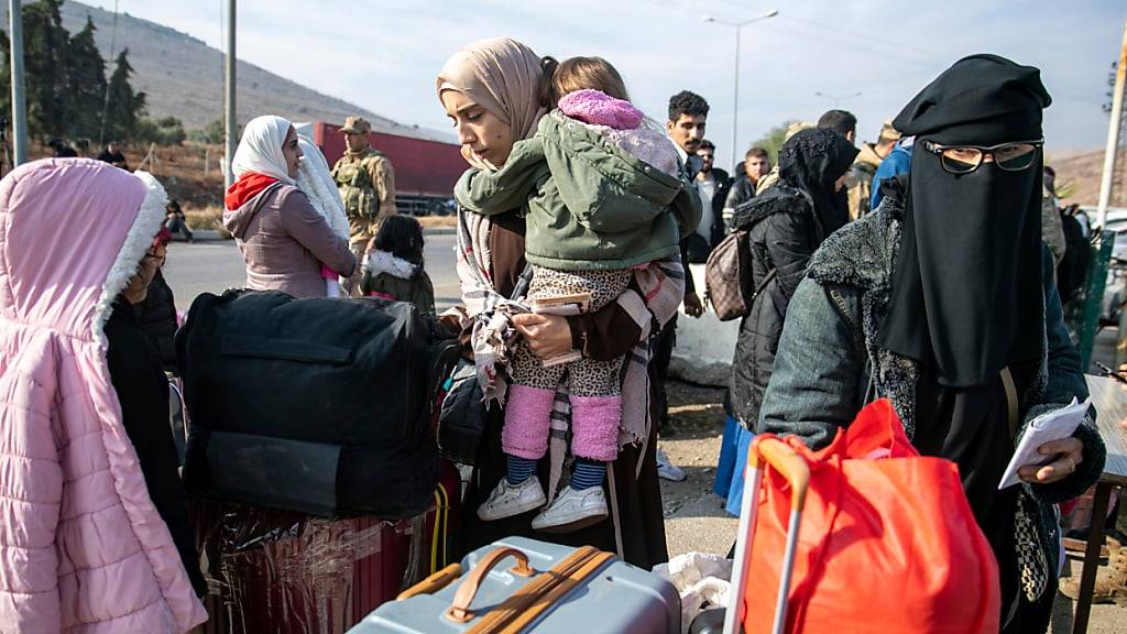 Syrische Familien warten am Cilvegozu-Grenzübergang in der Nähe der südtürkischen Stadt Antakya darauf, von der Türkei nach Syrien zu gelangen. Foto: Metin Yoksu/AP/dpa