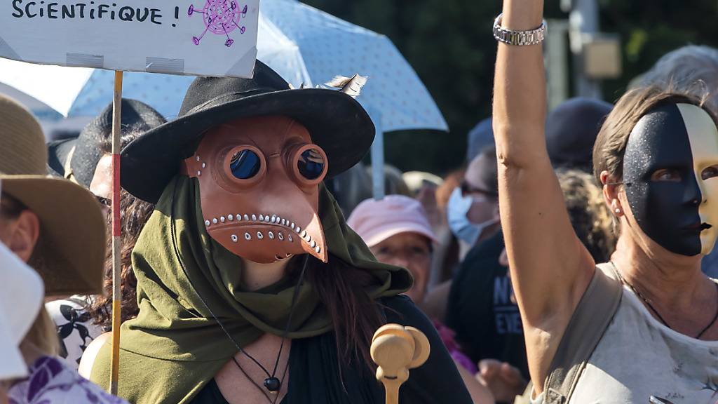 Eine Person (links) demonstrierte in Genf im Kostüm eines Pestdoktors. Die Schnabelmaske war im Mittelalter Teil der Arztausrüstung.