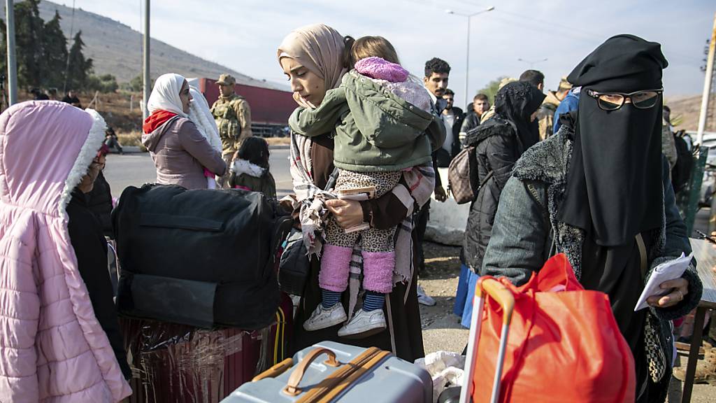 Syrische Familien warten am Cilvegozu Grenzübergang in der Nähe der südtürkischen Stadt Antakya darauf, von der Türkei nach Syrien zu gelangen. Foto: Metin Yoksu/AP/dpa