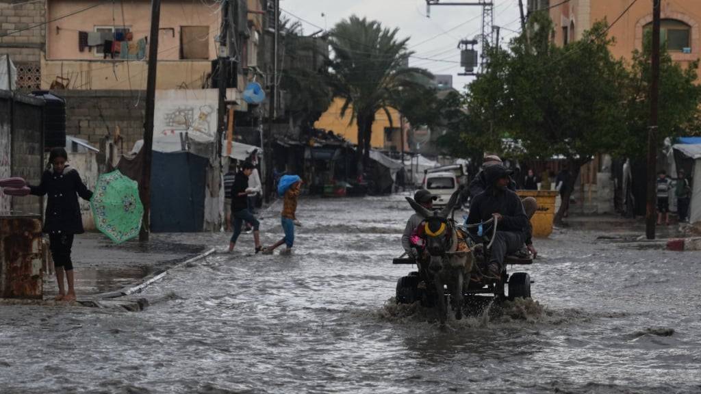 Palästinenser gehen durch eine überschwemmte Straße nach starken Regenfällen in Deir al-Balah, im zentralen Gazastreifen. Foto: Abdel Kareem Hana/AP/dpa
