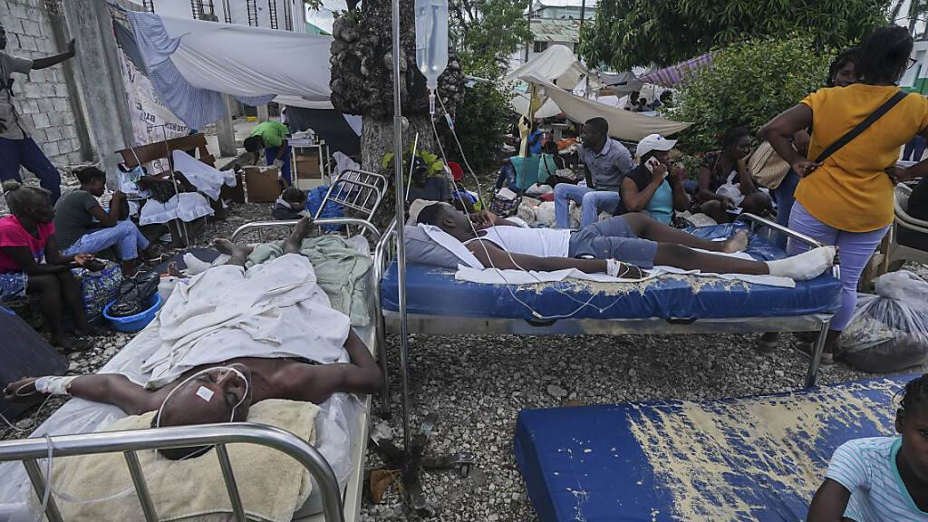 Verletzte liegen in Betten vor dem Krankenhaus Immaculée Conception in Les Cayes, zwei Tage nach einem Erdbeben der Stärke 7,2 im Südwesten des Landes. Nach dem Erdbeben in Haiti ist die Zahl der bestätigten Todesopfer auf 1419 gestiegen. Foto: Fernando Llano/AP/dpa