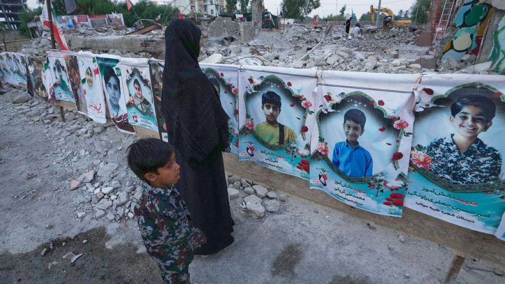 ARCHIV - Eine Frau und ein Kind betrachten die Porträts von Kindern und Lehrern, die bei einem US-Luftangriff am 28. Februar auf die Shajareh-Tayyebeh-Schule in Minab im Süden des Iran ums Leben gekommen sind. Foto: Vahid Salemi/AP/dpa (Archivbild)