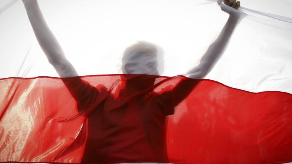 ARCHIV - Ein Demonstrant hält eine historische belarussische Fahne. Trotz eines Großaufgebots an Sicherheitskräften haben Zehntausende Menschen gegen den autoritären Staatschef Lukaschenko demonstriert. Foto: Uncredited/AP/dpa