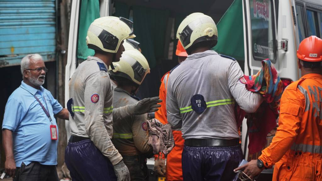 Rettungskräfte tragen nach einem Erdrutsch in Mumbai den Leichnam eines Opfers zu einem Krankenwagen. Foto: Rafiq Maqbool/AP/dpa