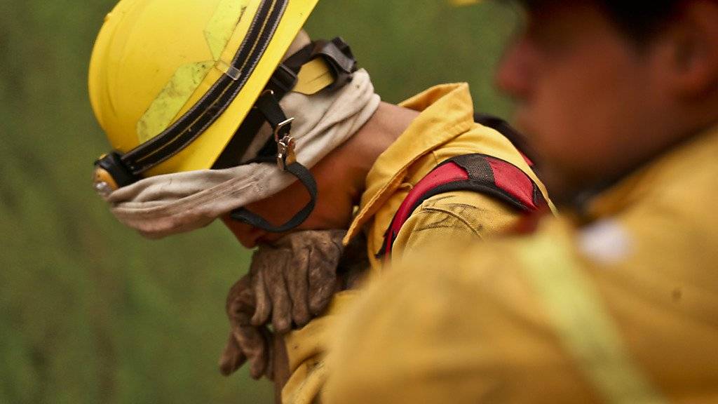 Chilenische Feuerwehrmänner bei einer Verschnaufpause in ihrem Kampf gegen die Brände