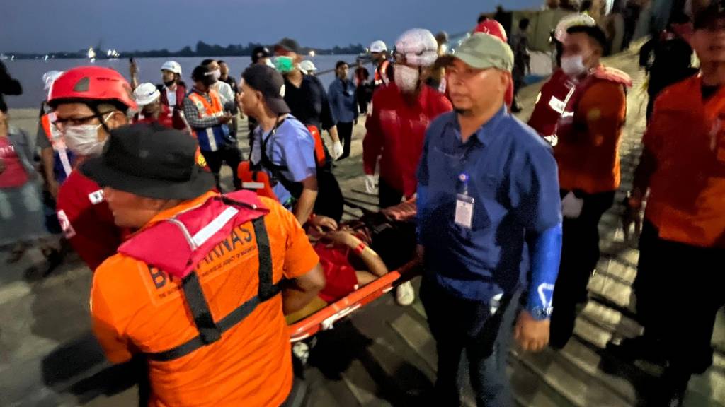 Rettungskräfte tragen in einem Hafen in Banjarmasin einen Überlebenden einer gekenterten Fähre auf einer Trage. Im Inselstaat Indonesien geriet eine Fähre in Seenot. Foto: Iman Satria/AP/dpa