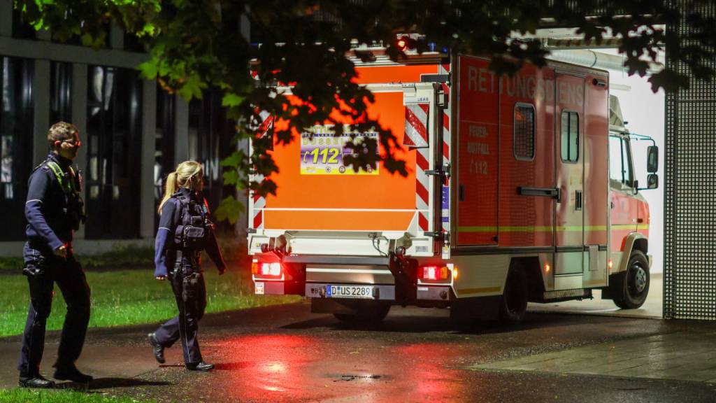 dpatopbilder - Polizisten laufen an einem ankommenden Rettungswagen vorbei, der eine deutsche Patientin in das Infektionszentrum der Uniklinik Düsseldorf bringt. Foto: Christoph Reichwein/dpa