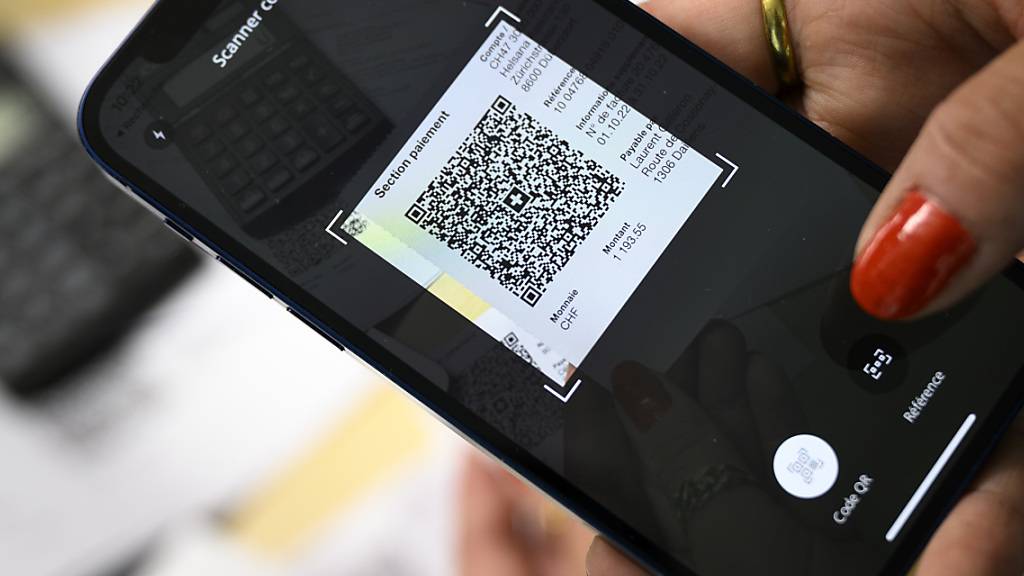 Eine Frau aus Lausanne scannt 2022 mit ihrem Mobiltelefon den QR-Code eines Einzahlungsscheins. (Archivbild)