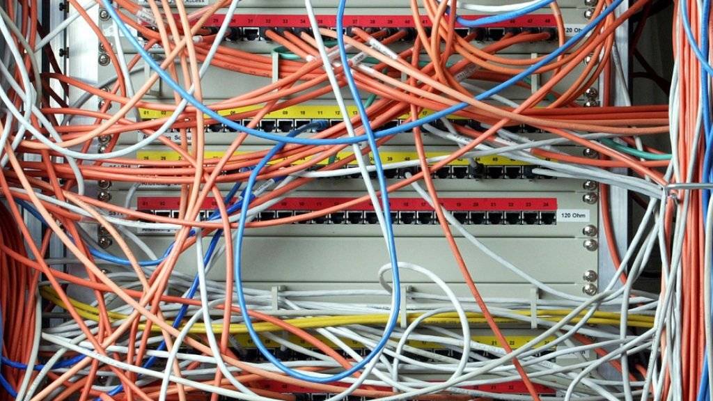 Ein Computer mit Datenkabeln. Das vom Bundestag beschlossene neue Gesetz sieht unter Auflagen Speicherfristen für Telekommunikationsdaten vor (Archiv)
