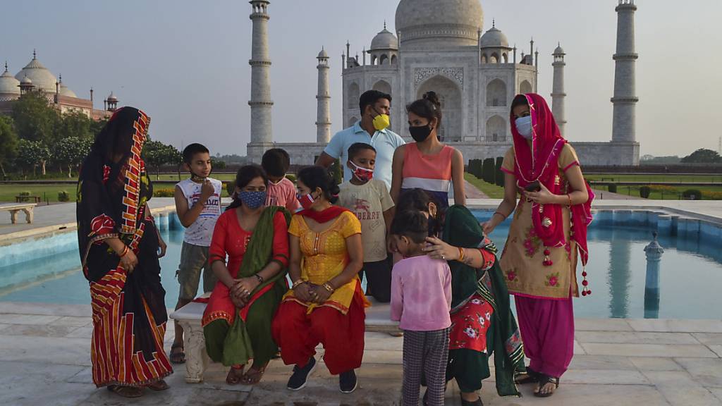 Eine Gruppe von Touristen sitzen auf einer Bank am Wasserbecken vor dem Mausoleum Taj Mahal. Aufgrund des Rückgangs von Corona-Neuinfektionen öffnet die Regierung in Indien mehrere Denkmäler. Foto: Uncredited/AP/dpa