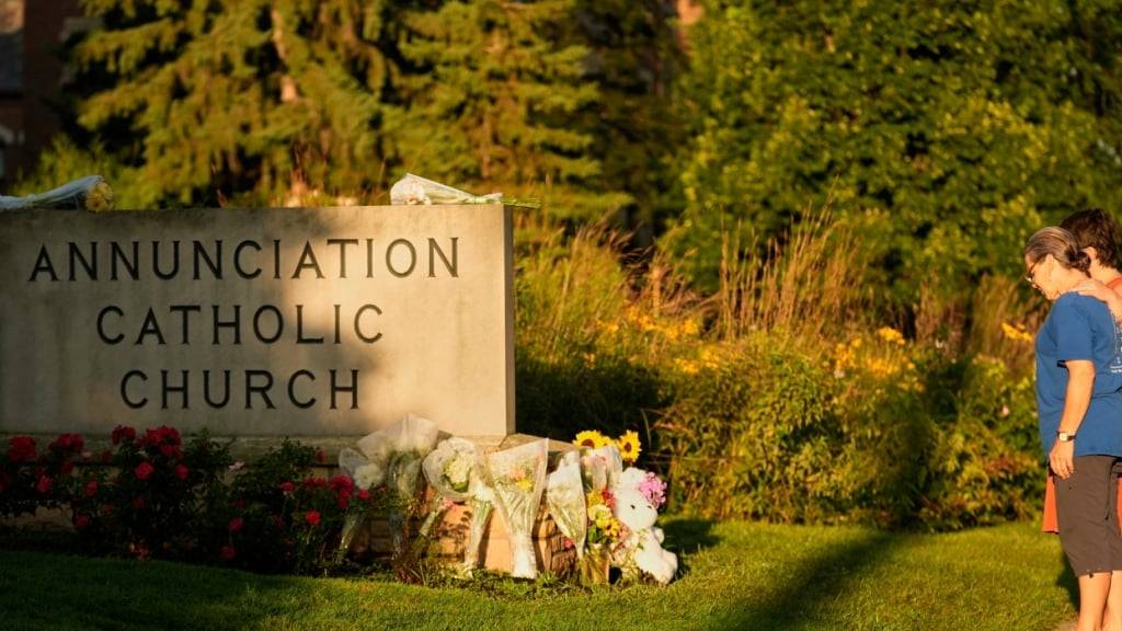 Menschen besuchen eine behelfsmäßige Gedenkstätte an der Annunciation Catholic Church, nach den Schüssen im Umfeld einer katholischen Schule mit zwei toten Kindern. Foto: Abbie Parr/AP/dpa