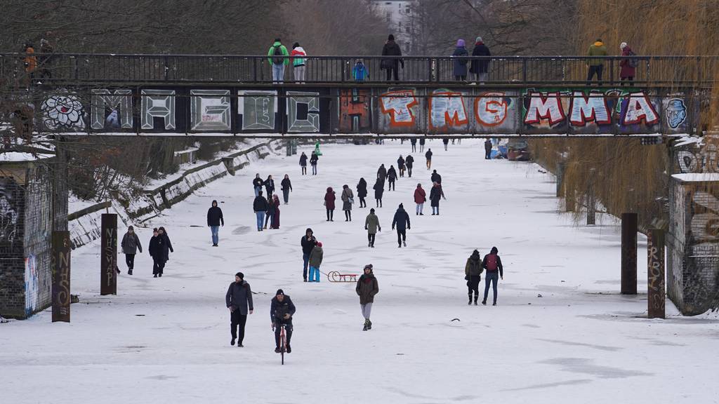 Menschen spazieren am Montag auf dem zugefrorenem Landwehrkanal in Berlin. Am Tag zuvor stieg hier eine Technoparty. 
