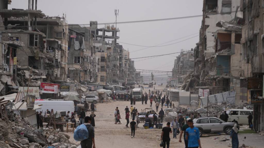 ARCHIV - Palästinenser gehen in der Stadt Gaza eine Straße entlang, die von zerstörten Gebäuden umgeben ist. Foto: Abdel Kareem Hana/AP/dpa/Archivbild