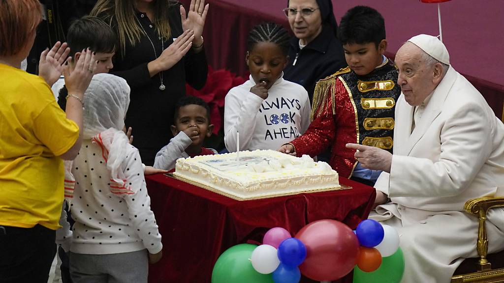 Papst Franziskus wird ein Kuchen angeboten, während er in der Paul VI.-Halle im Vatikan seinen Geburtstag mit Kindern feiert. Foto: Alessandra Tarantino/AP/dpa