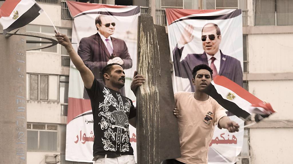 Zwei Anhänger des ägyptischen Präsidenten al-Sisi schwenken ägyptische Nationalfahnen. Foto: Amr Nabil/AP/dpa