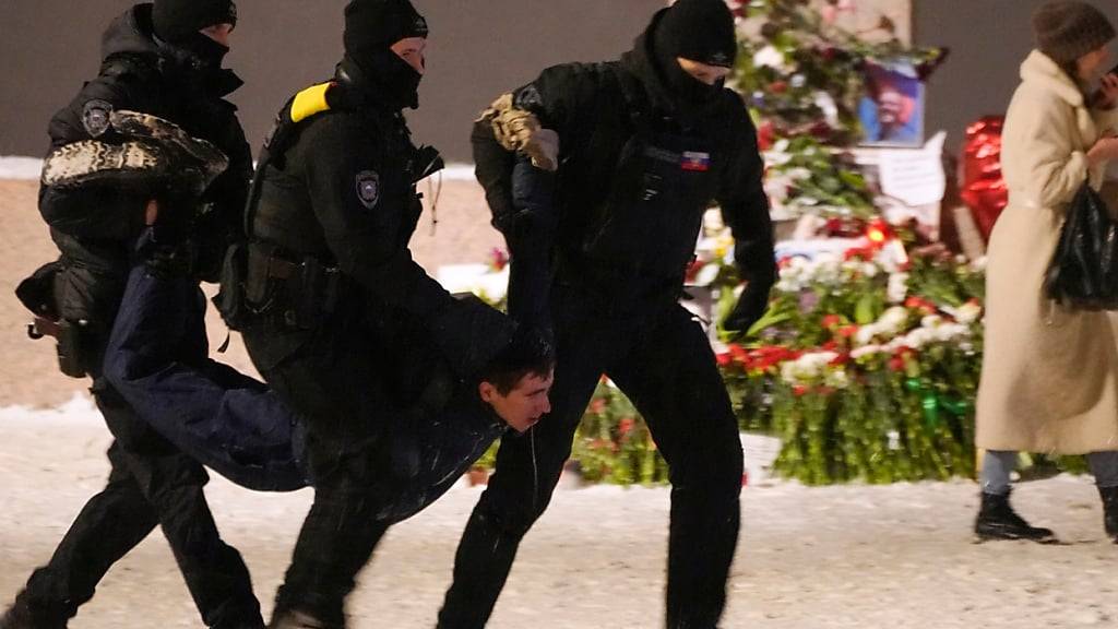 ARCHIV - Polizeibeamte halten im Februar einen Mann fest, der Blumen zu Ehren von Alexej Nawalny an einem Denkmal für die Opfer der sowjetischen Unterdrückung in St. Petersburg, Russland, niedergelegt hat Foto: Uncredited/AP/dpa